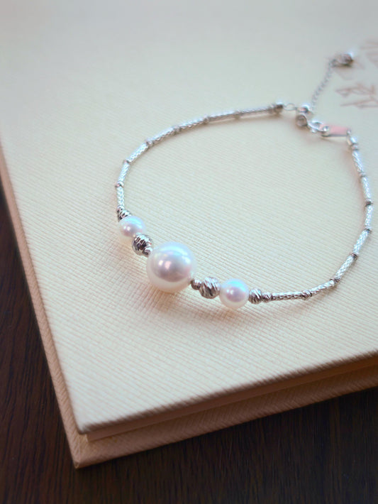 Cyrene Moirae Pearl Bar Bracelet flat lay, 925 silver bracelet with aurora freshwater pearls on beige background