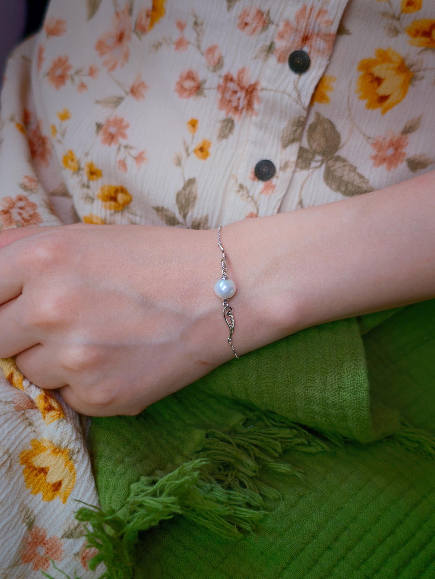 Side view of Cyrene Pinion Pearl Bracelet on model wrist, ultra-fine silver chain with wing and pearl detail