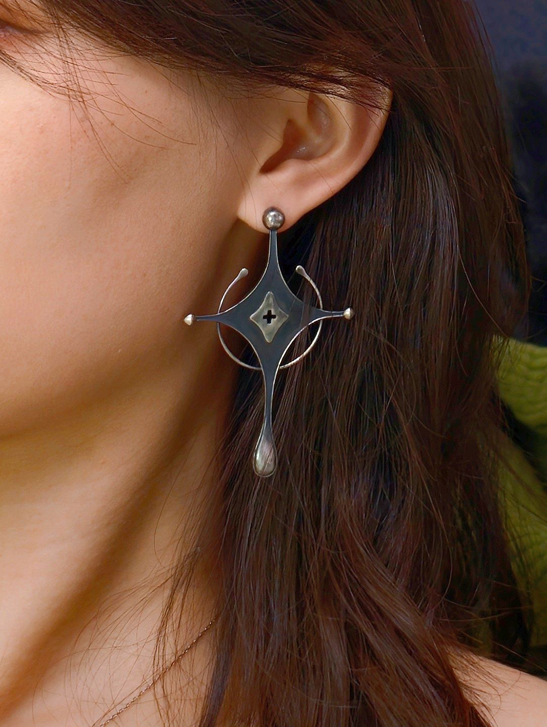 Close-up of Cyrene Axiom Cross sterling silver earring on model, 7cm drop earring with cross and teardrop detail