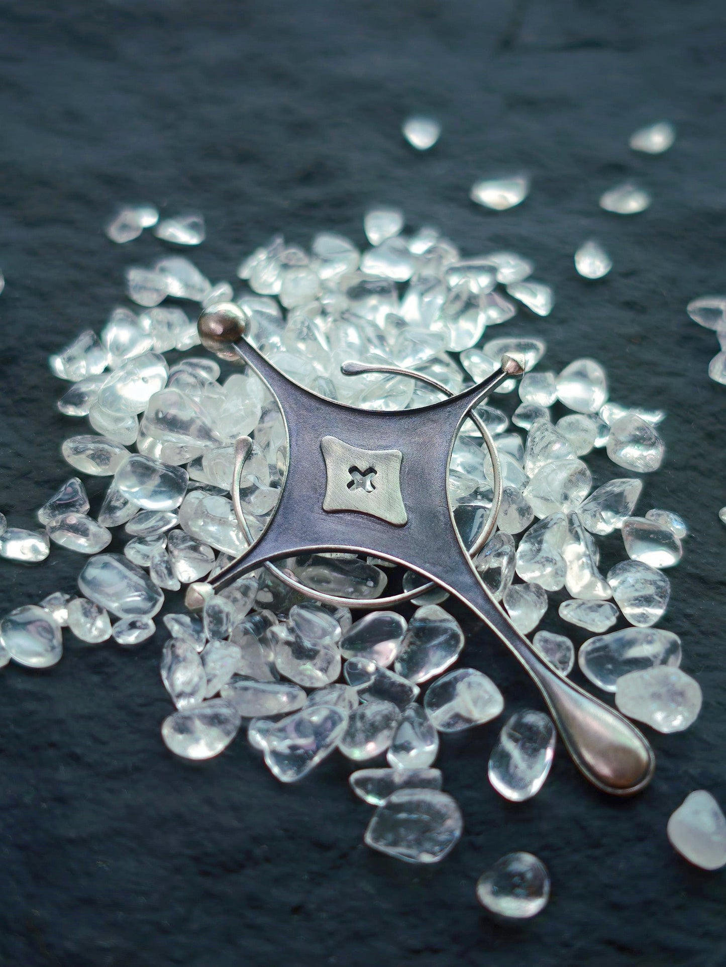 Cyrene Axiom Cross 925 silver earring angled flat lay, asymmetric indie jewelry handcrafted statement piece