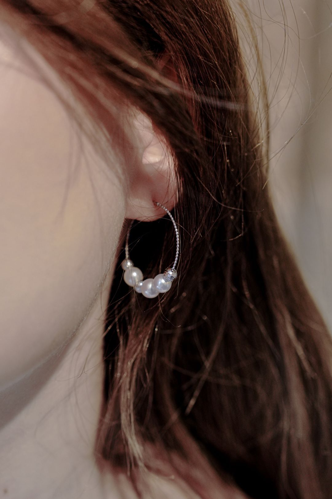 Effortless chic styling showing a model wearing Cyrene's perfectly sized pearl hoop earrings peeking elegantly through her hair