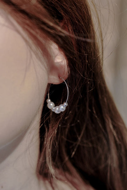 Effortless chic styling showing a model wearing Cyrene's perfectly sized pearl hoop earrings peeking elegantly through her hair