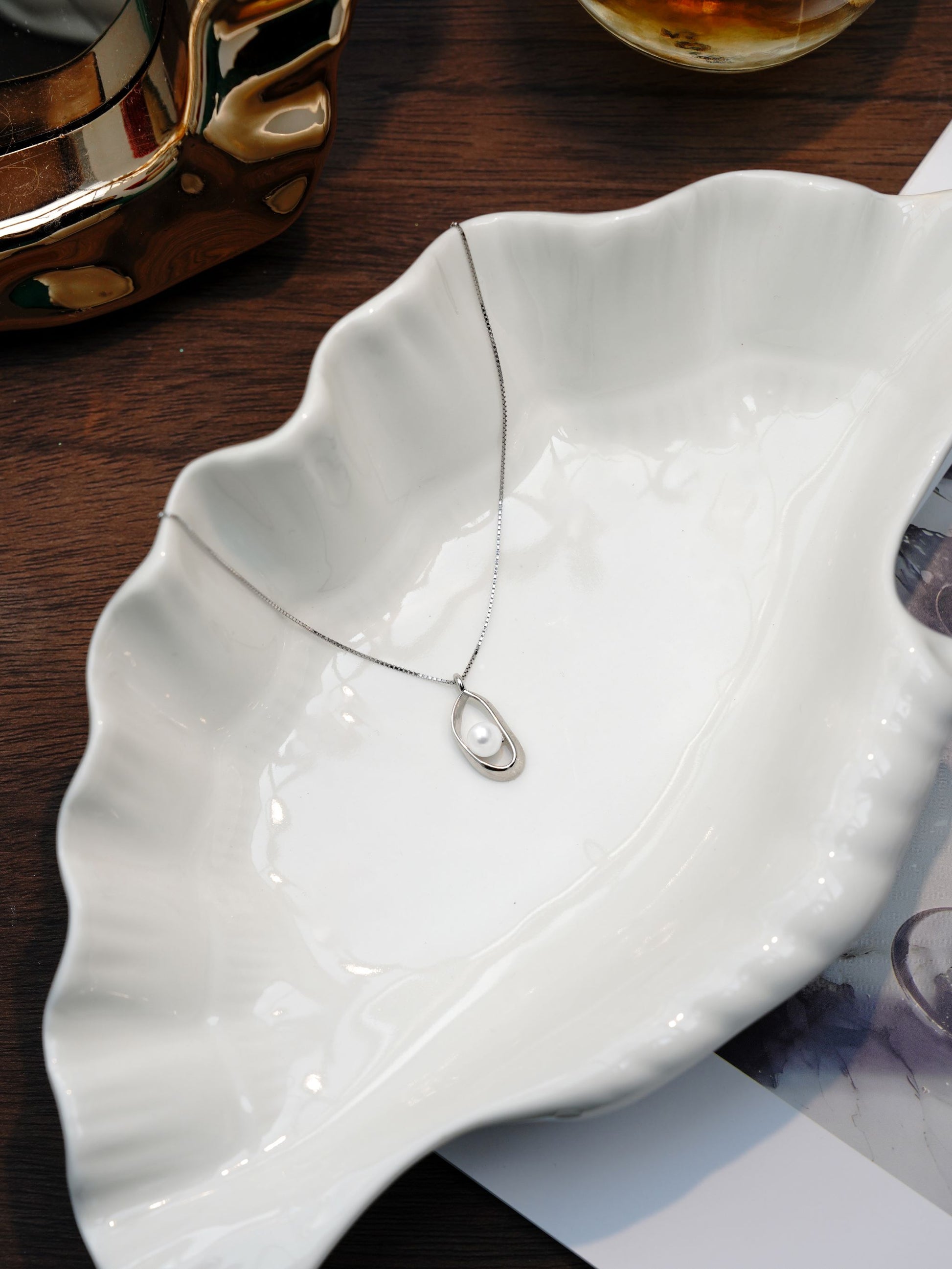 Delicate Cyrene freshwater pearl necklace with a simple silver frame resting beautifully in a white ceramic dish for an everyday look