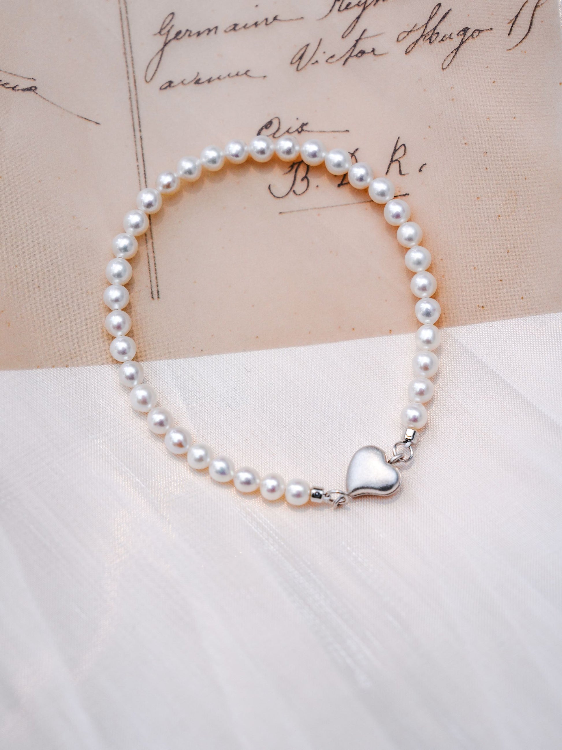 A dainty Cyrene seed pearl bracelet featuring a 925 silver heart magnetic clasp, beautifully displayed with a gentle aesthetic
