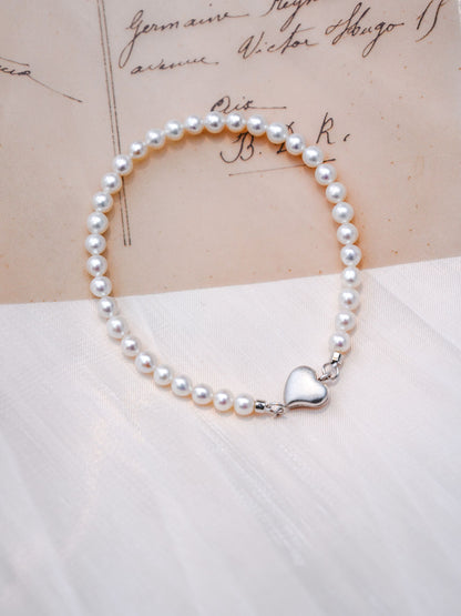 A dainty Cyrene seed pearl bracelet featuring a 925 silver heart magnetic clasp, beautifully displayed with a gentle aesthetic