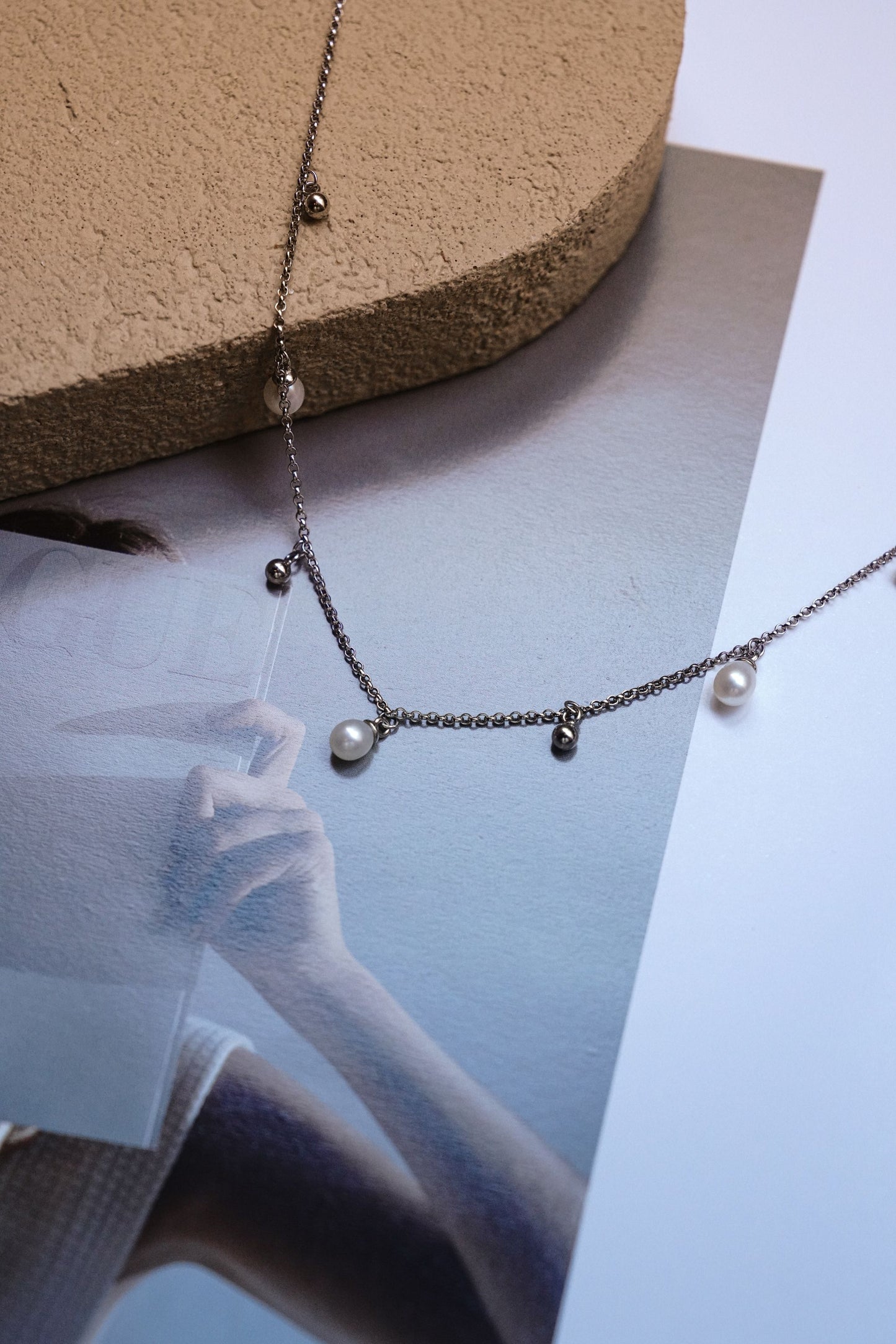 Close-up of a dainty 925 silver station necklace by Cyrene, featuring playful sliding teardrop freshwater pearls and small silver beads