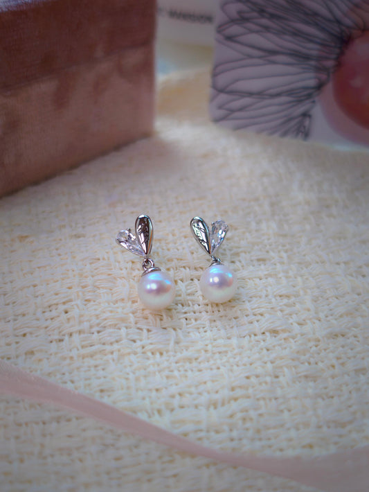 Close-up of Cyrene by Elsie's Demi Pearl Earrings showing pear-cut CZ and Luck-engraved 925 silver teardrops forming a heart stud