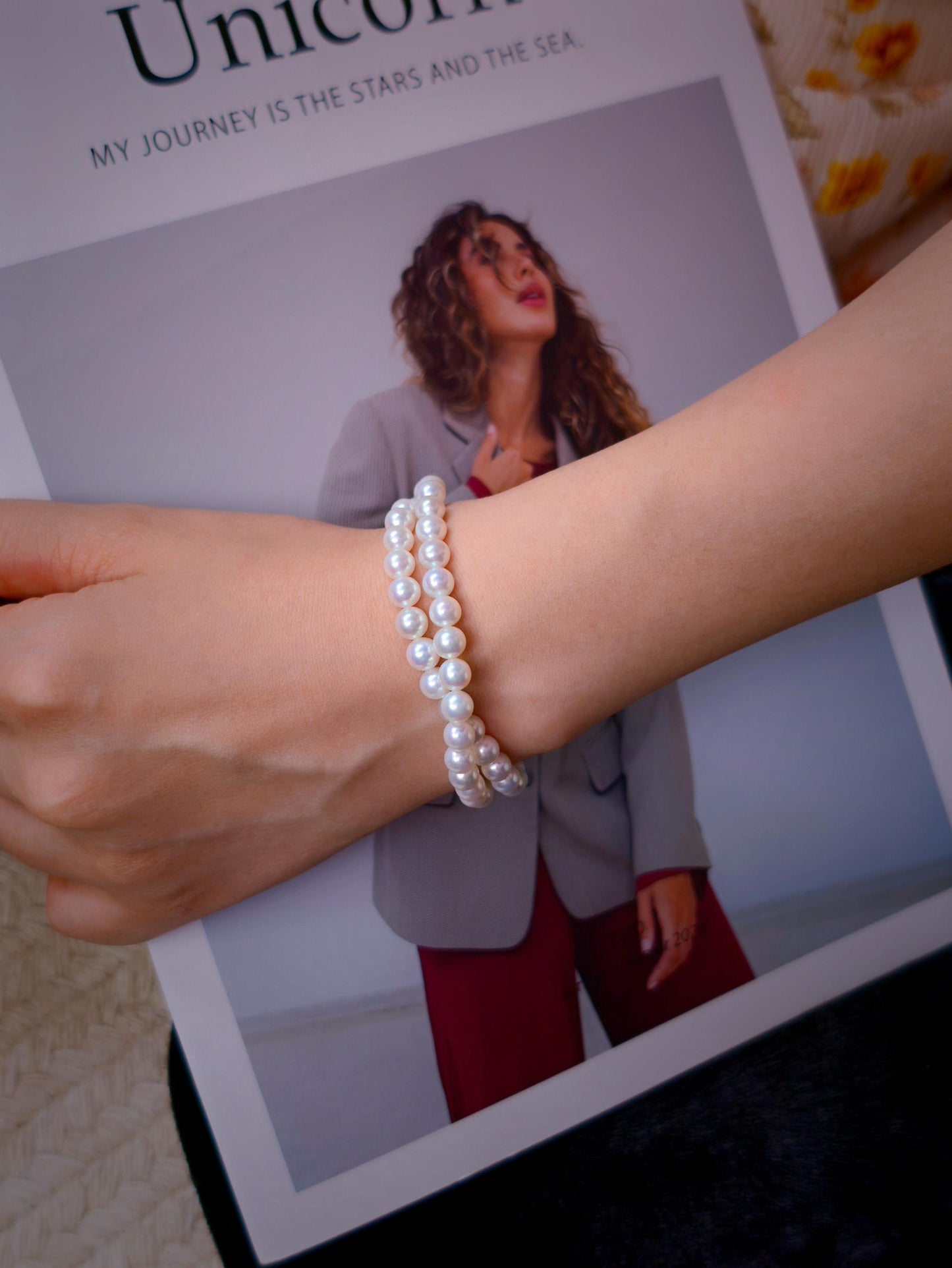 Cyrene by Elsie Duet Pearl Bracelet styled on wrist against a fashion magazine background