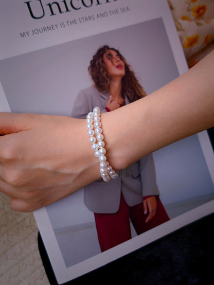 Cyrene by Elsie Duet Pearl Bracelet styled on wrist against a fashion magazine background
