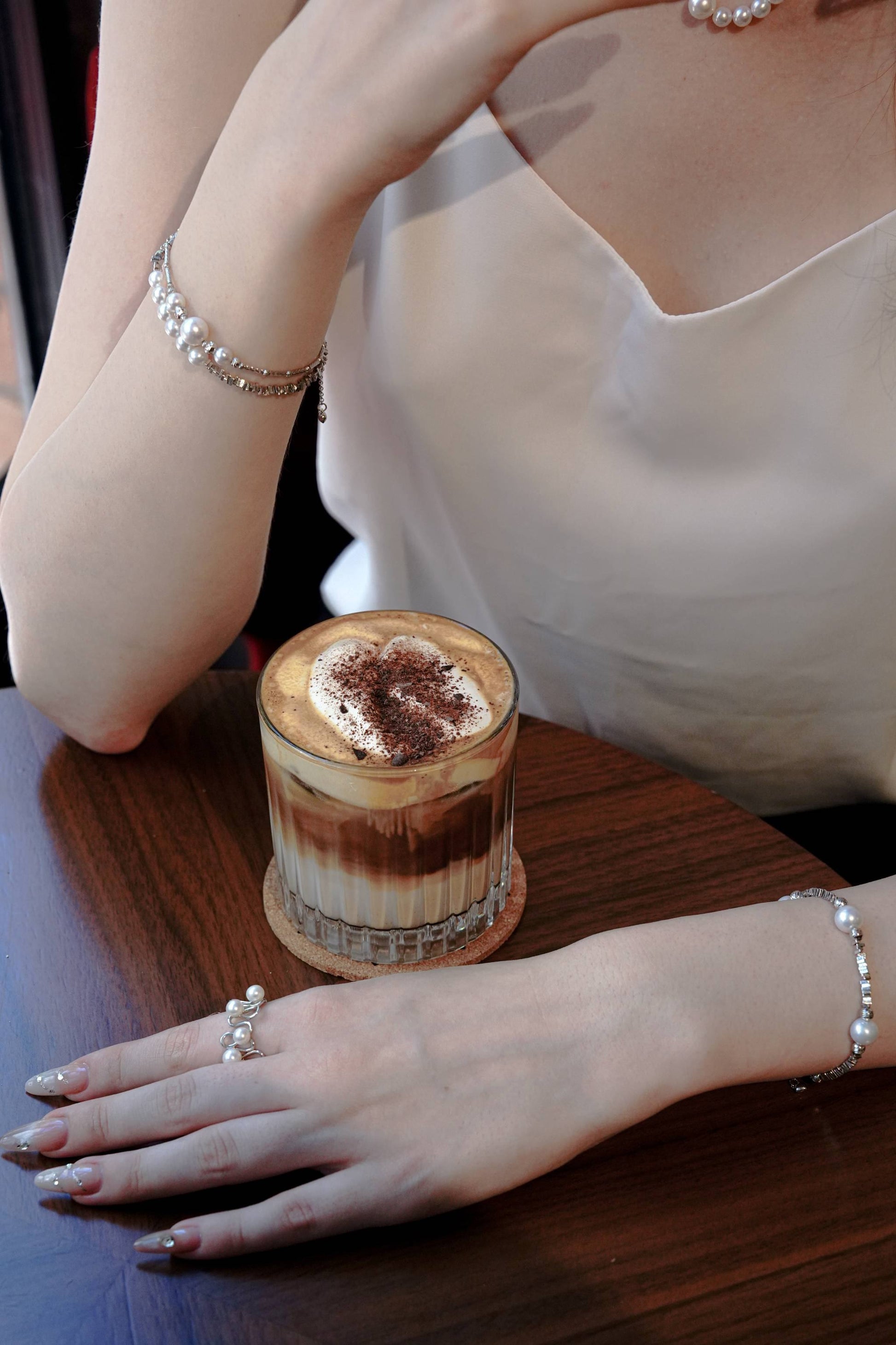 Lifestyle shot of a Cyrene multi-pearl silver open ring styled for casual everyday chic wear holding a coffee glass