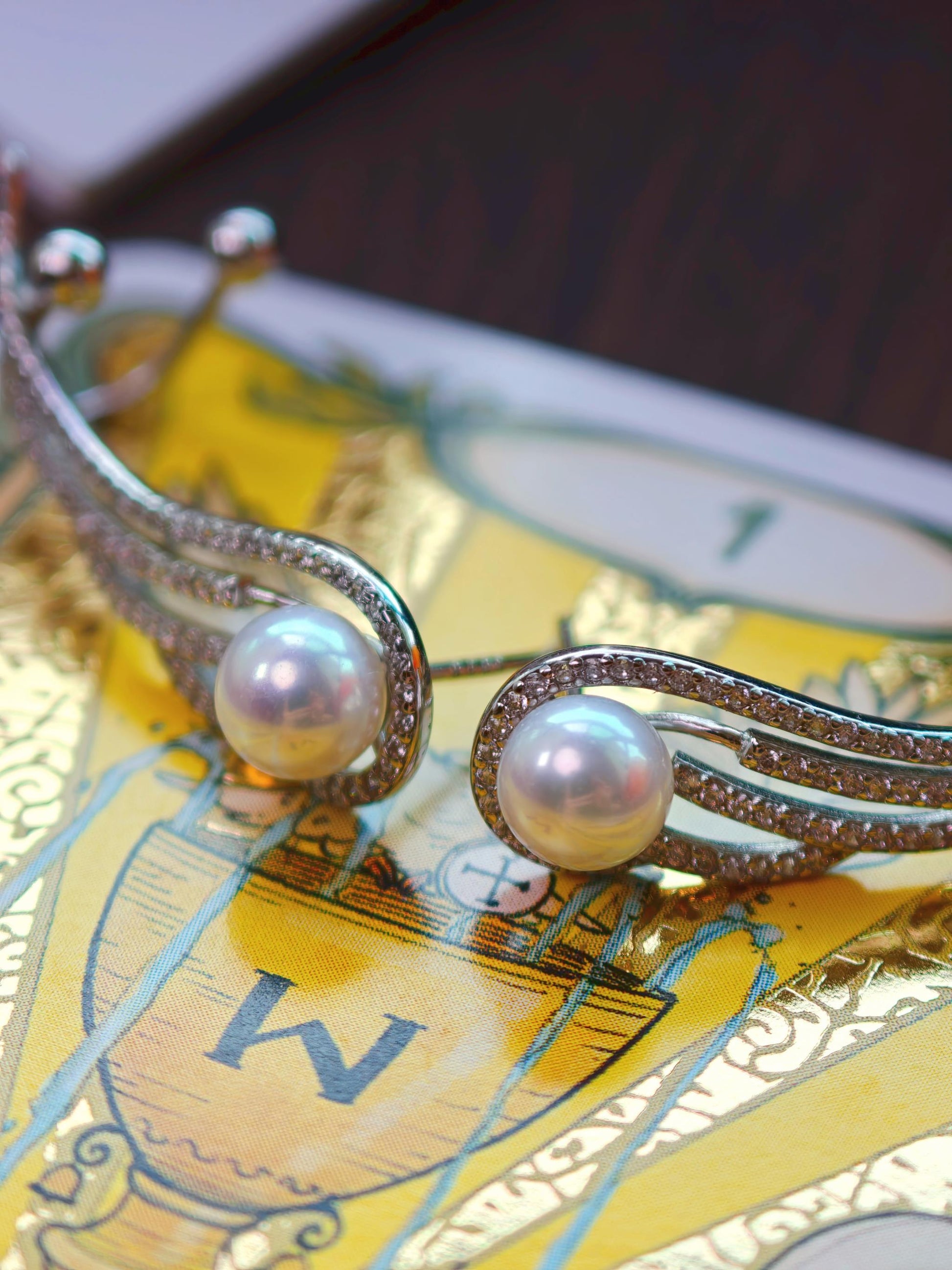 Close-up of Cyrene Featherrise Wing earring, aurora freshwater pearl 6-7mm and pavé CZ silver wing detail