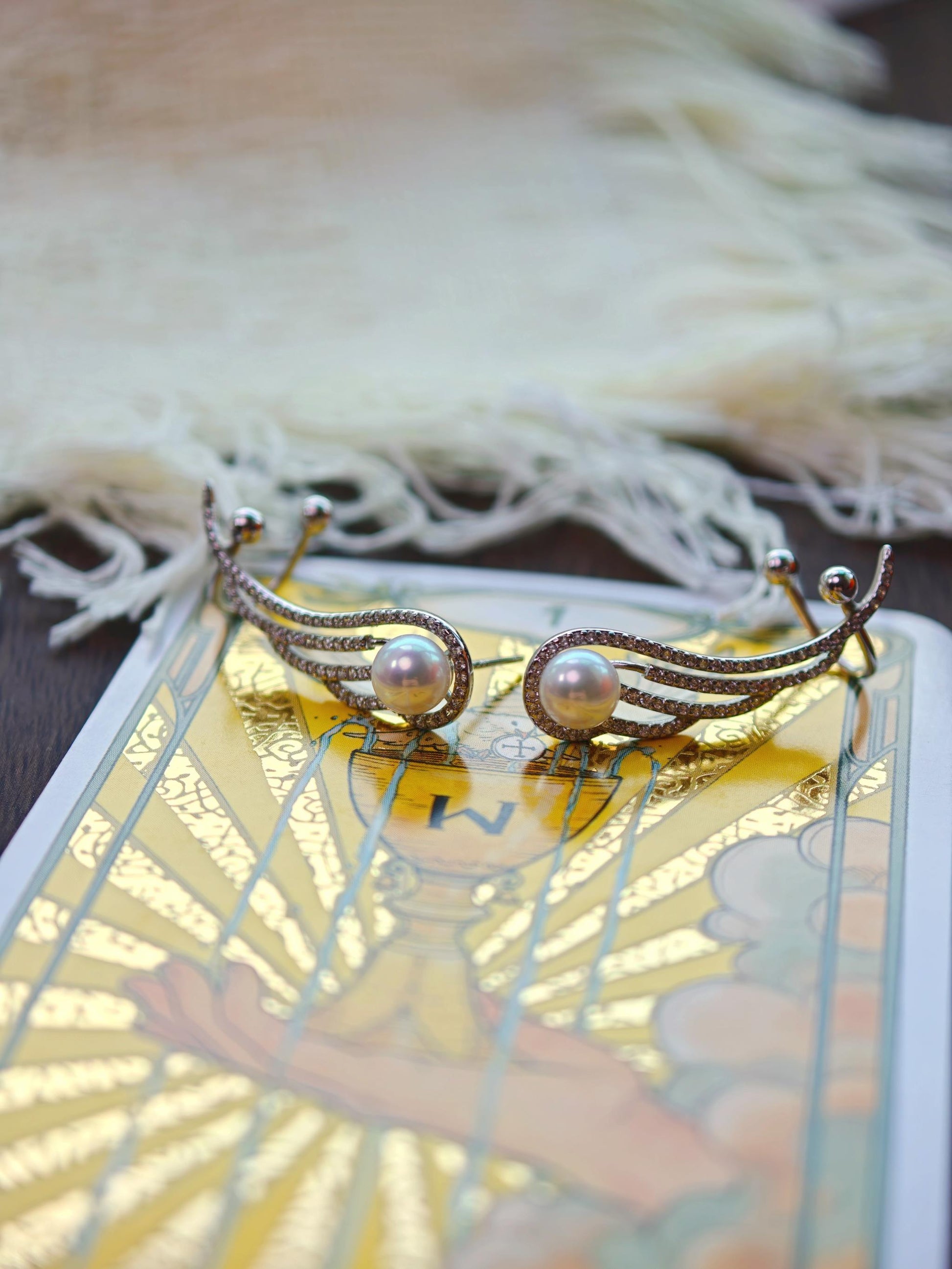 Cyrene Featherrise Wing pearl ear climber earring pair flat lay, 925 silver wing with aurora freshwater pearl