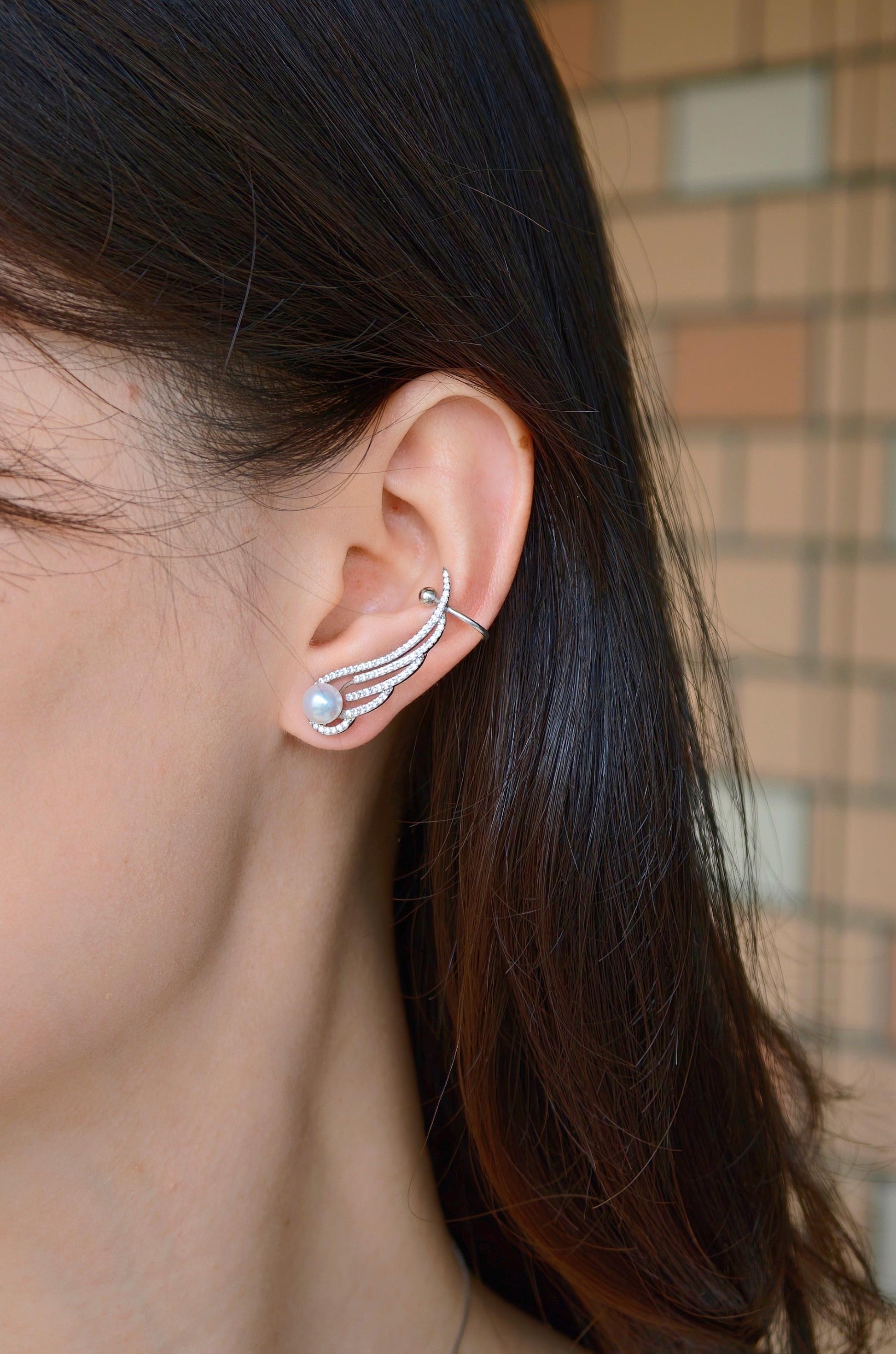 Model wearing Cyrene Featherrise Wing pearl ear climber, silver wing rising along ear with aurora pearl stud