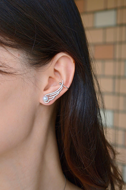 Model wearing Cyrene Featherrise Wing pearl ear climber, silver wing rising along ear with aurora pearl stud