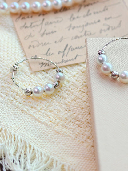 Close-up of Cyrene Halo Pearl Hoop Earring, three aurora freshwater pearls with textured silver bead spacers