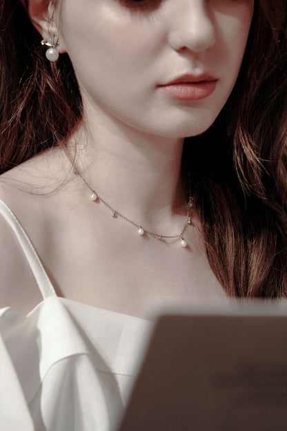 A versatile effortless chic look featuring a woman reading, styled with Cyrene's dynamic silver chain necklace with delicate pearl drops