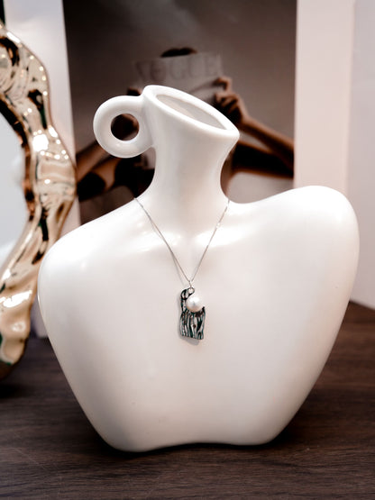 Close-up of a Cyrene necklace featuring an irregular liquid silver pendant with a beautiful water-wave texture and an embedded pearl.