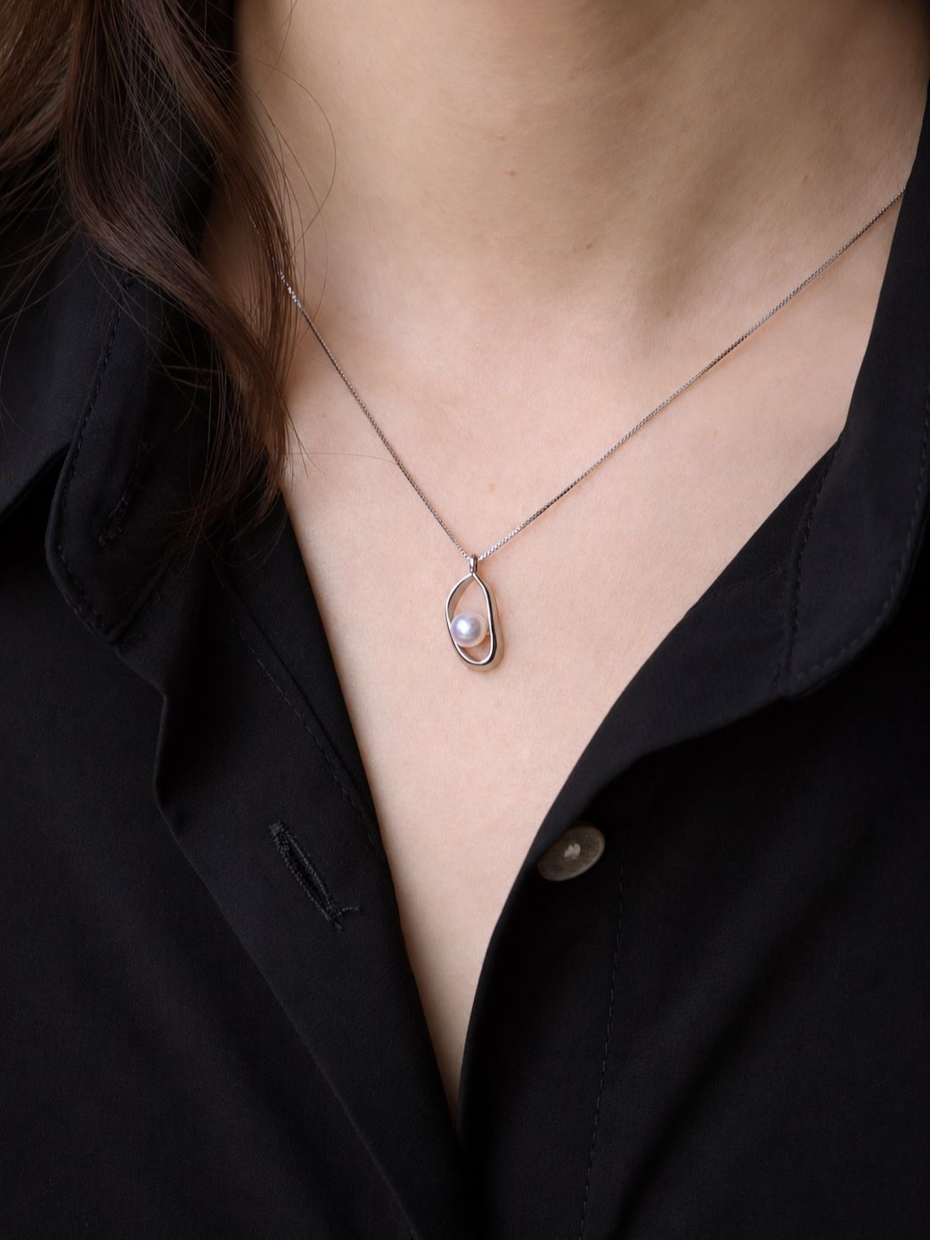 Loop Pearl Necklace worn on the neck in a close-up view, showing the freshwater pearl and sculptural 925 sterling silver loop pendant