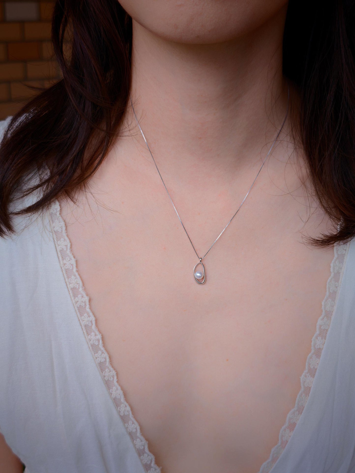 Cyrene Loop Pearl Necklace on neck with lace neckline — minimalist silver pendant with freshwater pearl detail