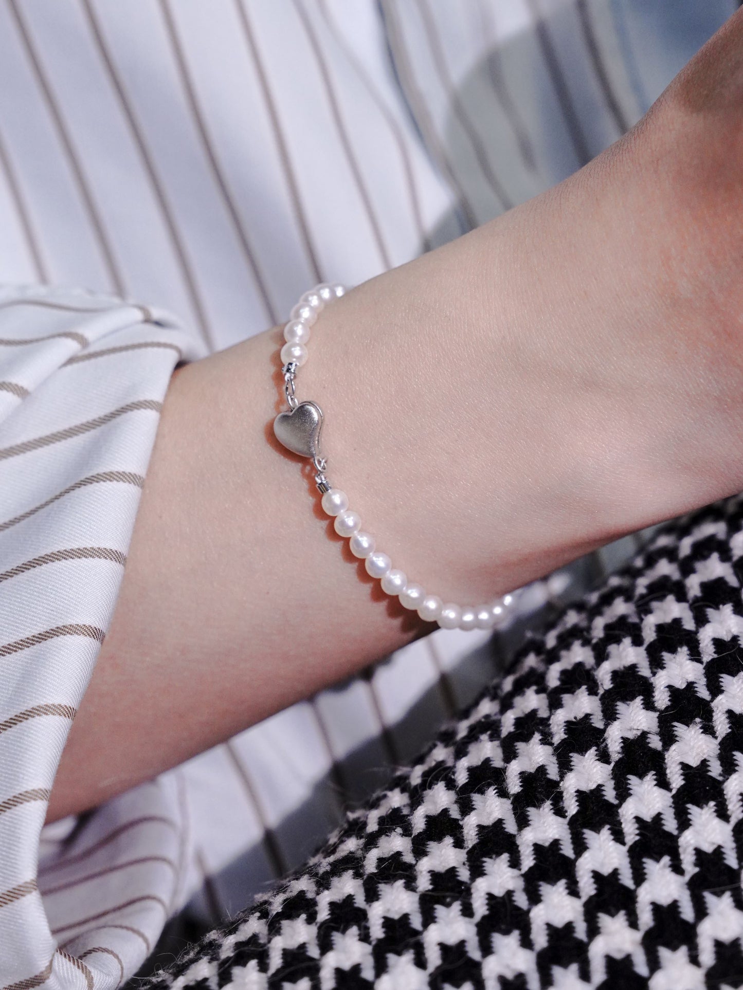 A minimalist everyday seed pearl bracelet by Cyrene gracefully accentuating a woman's wrist with its soft luster.