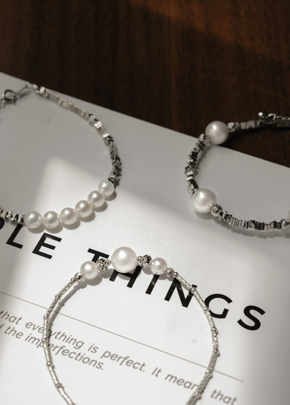 Minimalist Cyrene jewelry highlighting a stunning three-pearl centerpiece and carved silver tube chain, displayed on a modern magazine