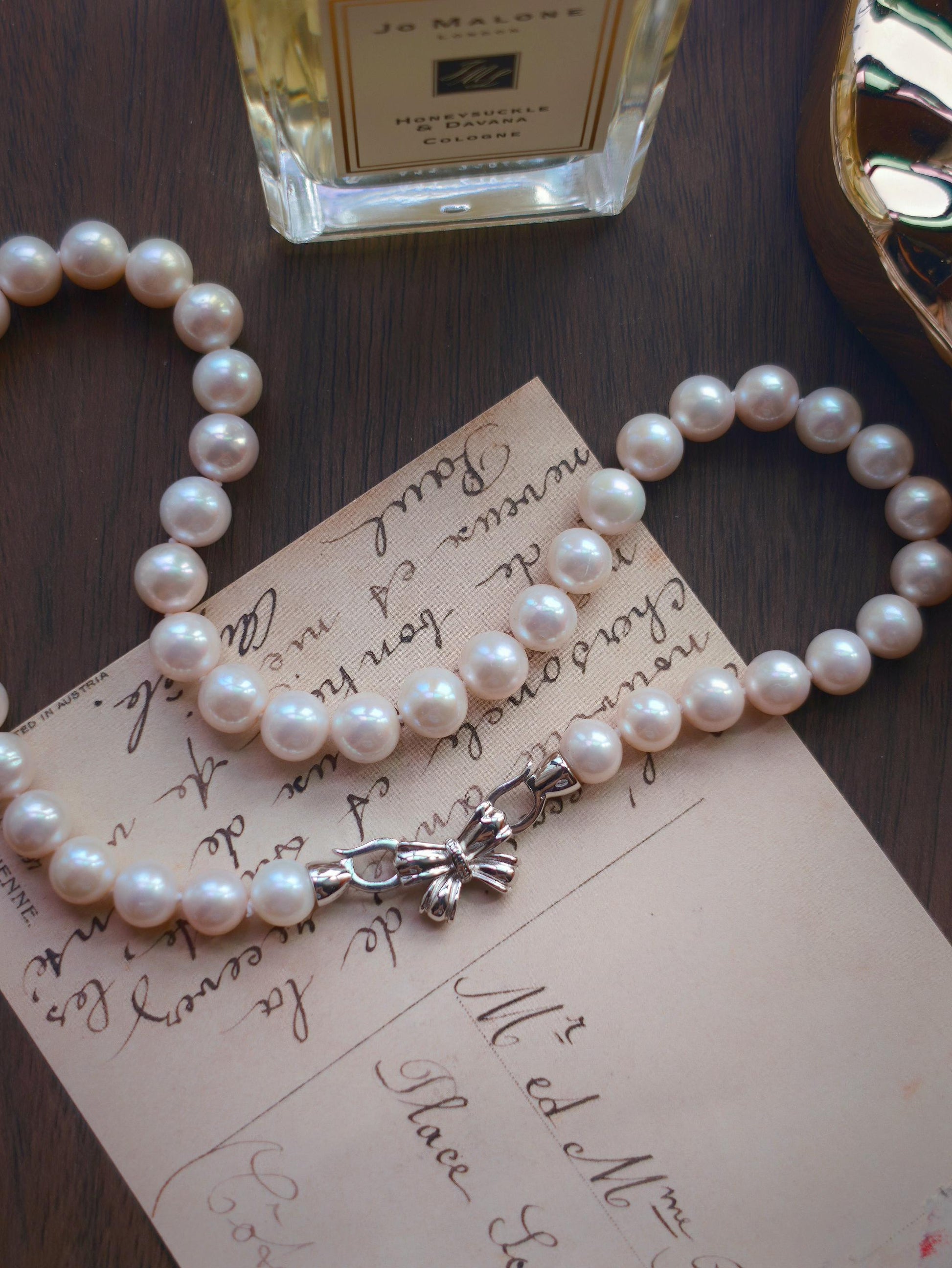 Cyrene by Elsie pearl necklace styled on a vintage postcard, showing 9mm near-round freshwater pearls