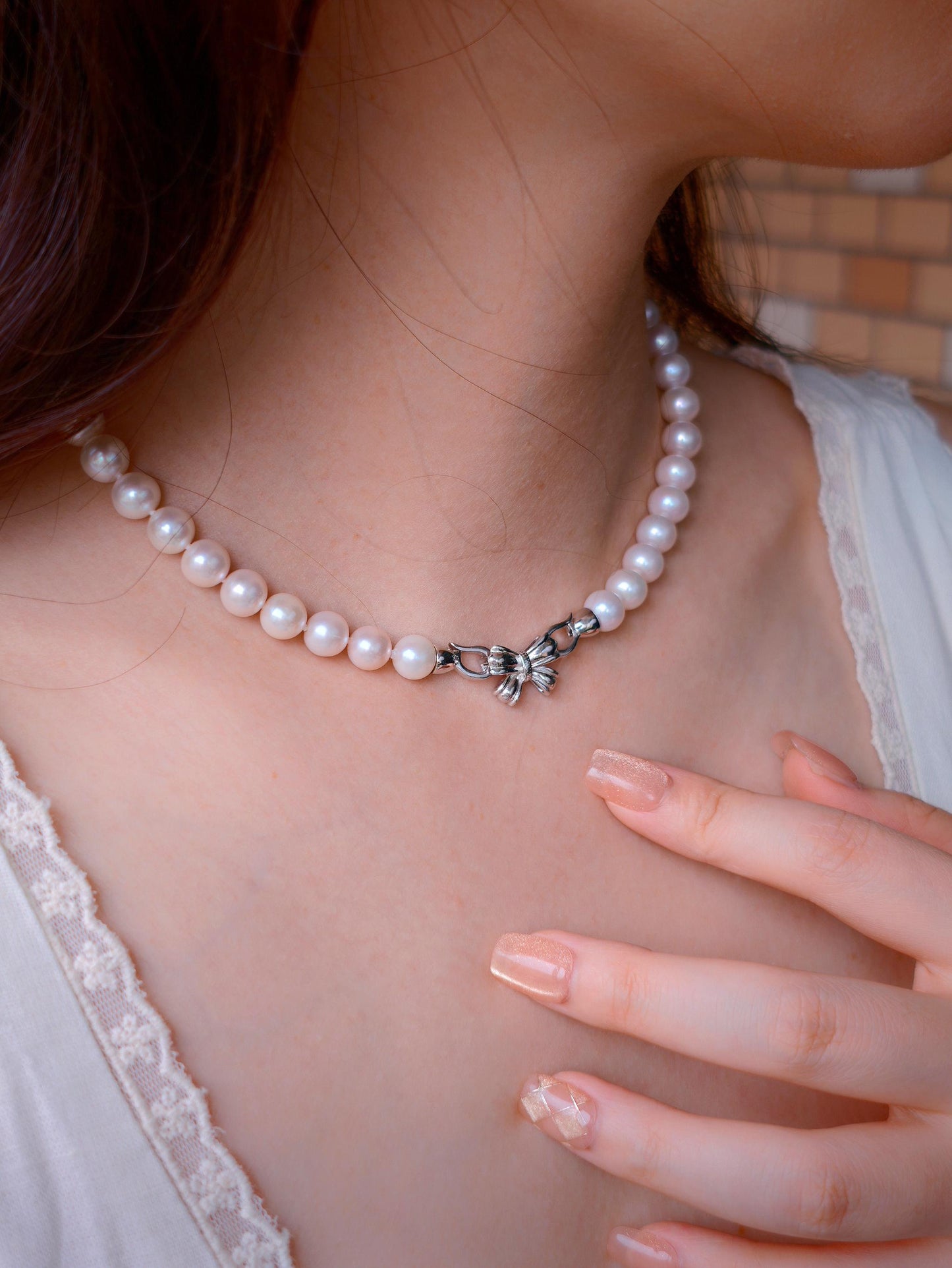 Model wearing Cyrene by Elsie's pearl necklace with the sterling silver bow clasp turned to the front