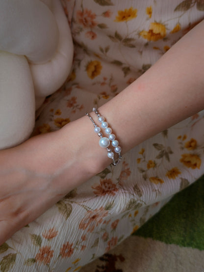 Cyrene Moirae Pearl Bar Bracelet stacked with another bracelet on wrist, layered pearl jewelry styling