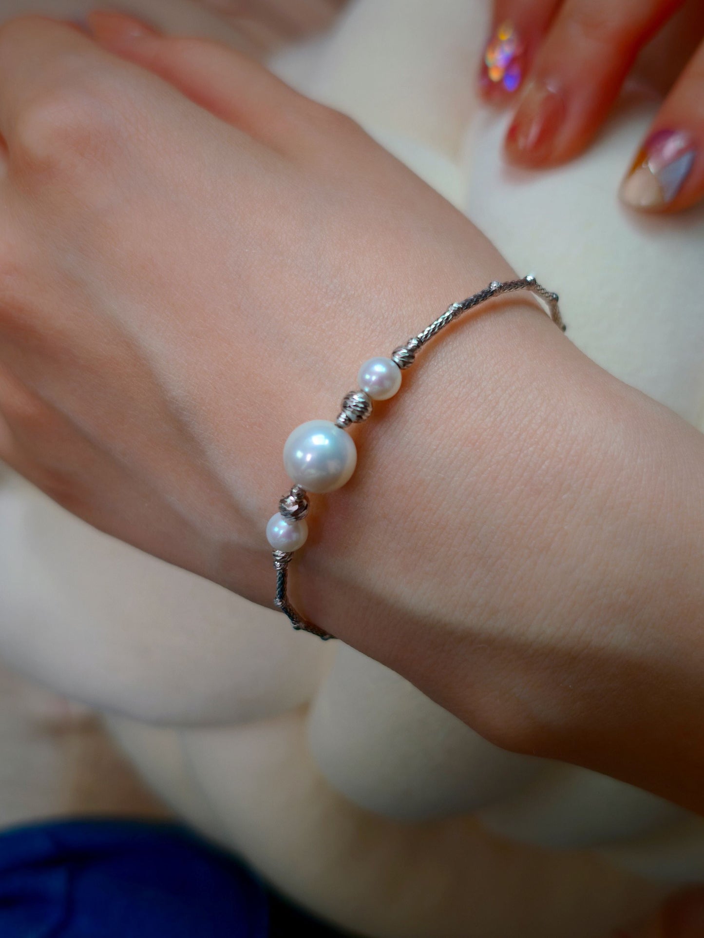Close-up of Cyrene Moirae Pearl Bar Bracelet on wrist, aurora freshwater pearl and silver bar detail