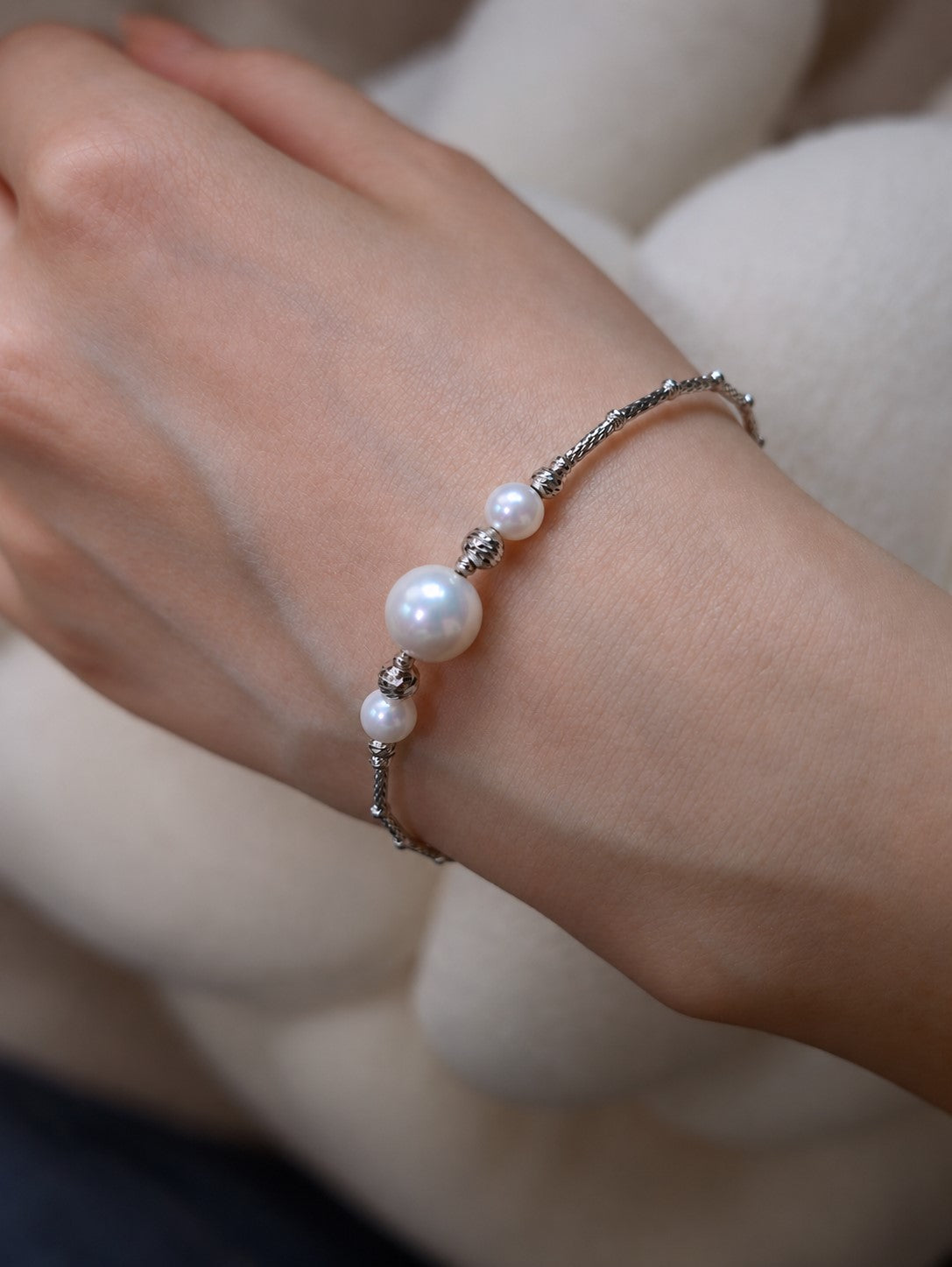 Close-up of Cyrene Moirae Pearl Bar Bracelet on wrist, aurora freshwater pearl and silver bar detail
