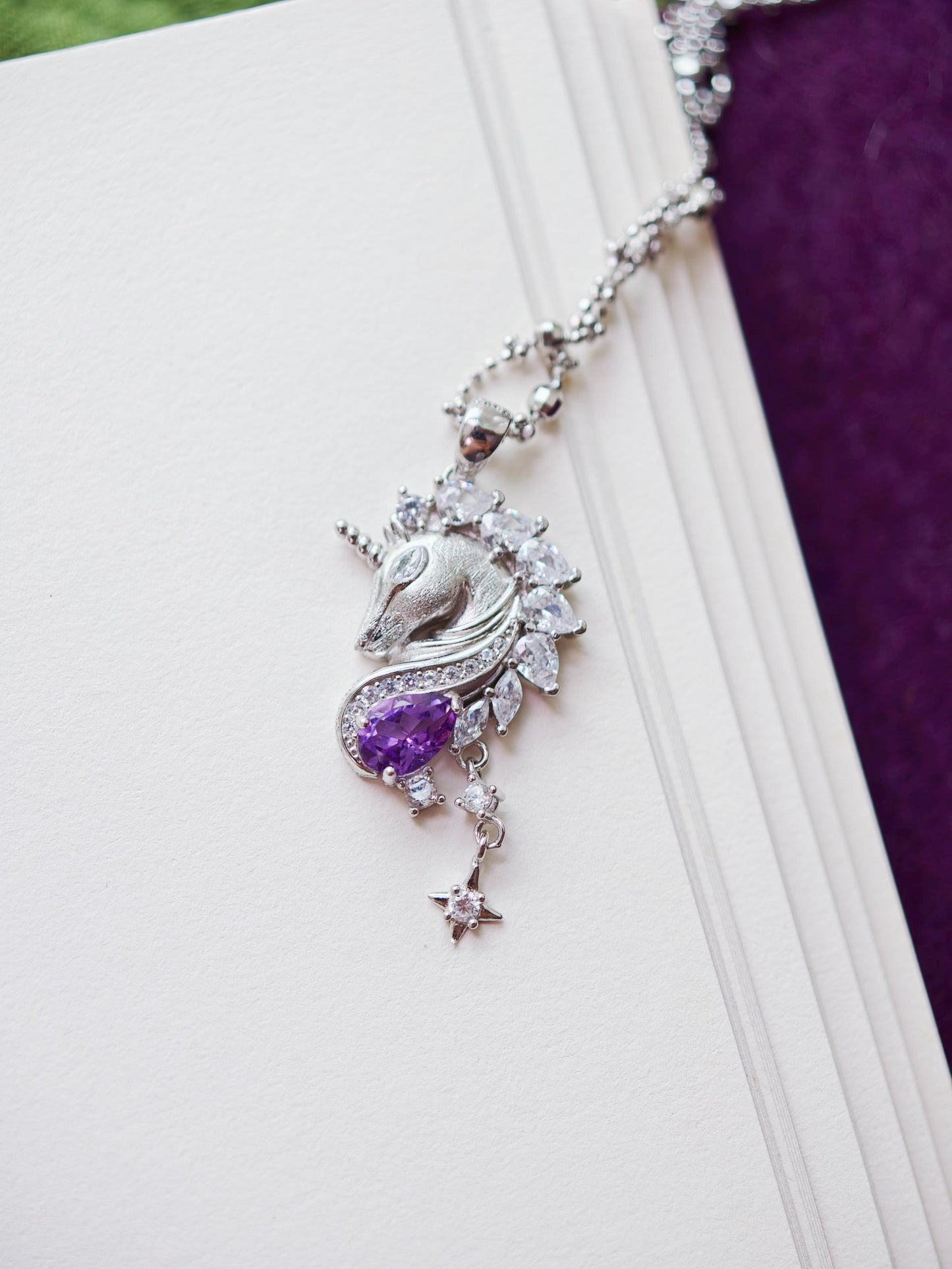 Close-up of Cyrene Moonglass Unicorn silver necklace pendant, natural amethyst teardrop and marquise CZ detail