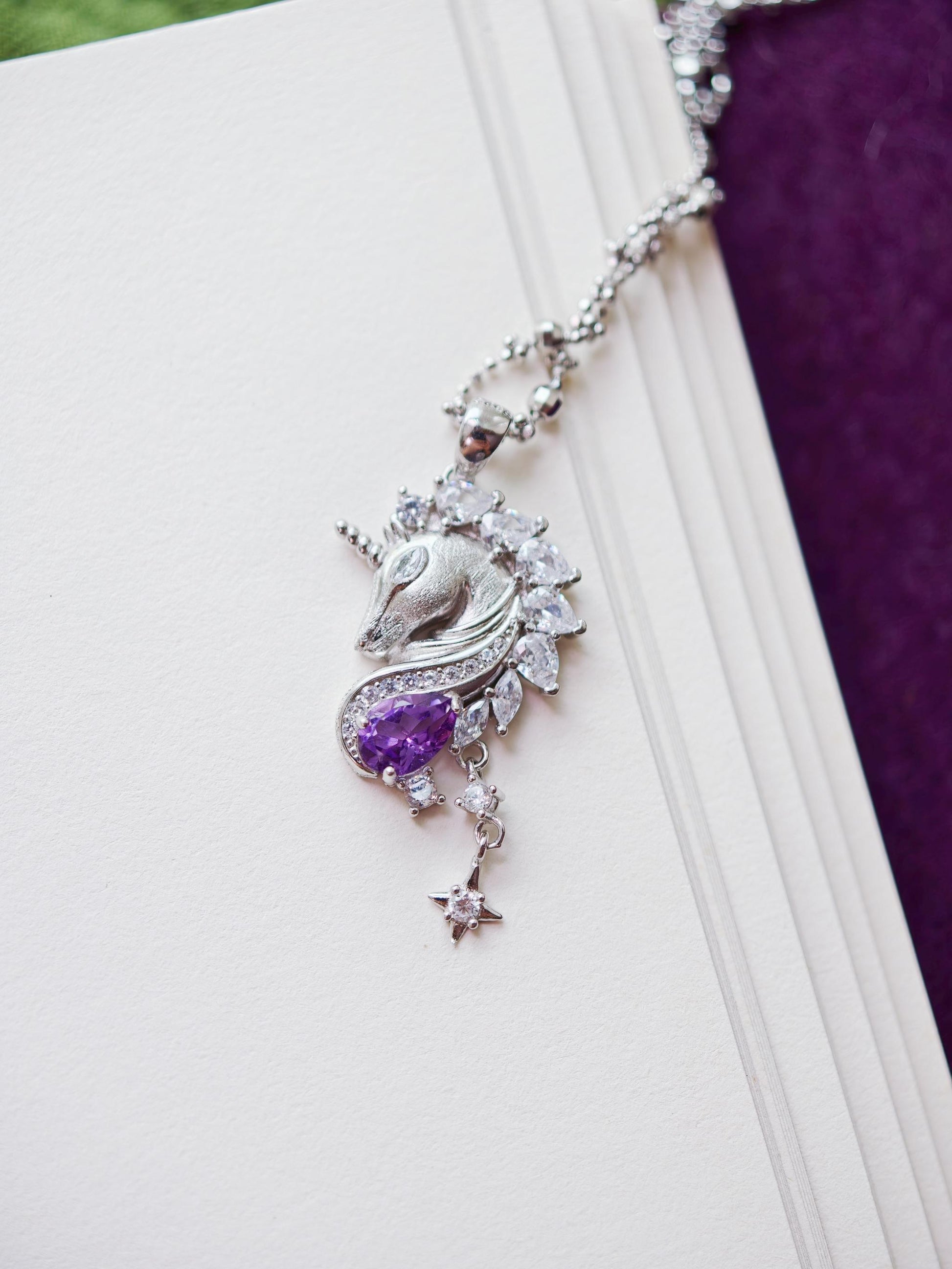 Close-up of Cyrene Moonglass Unicorn silver necklace pendant, natural amethyst teardrop and marquise CZ detail