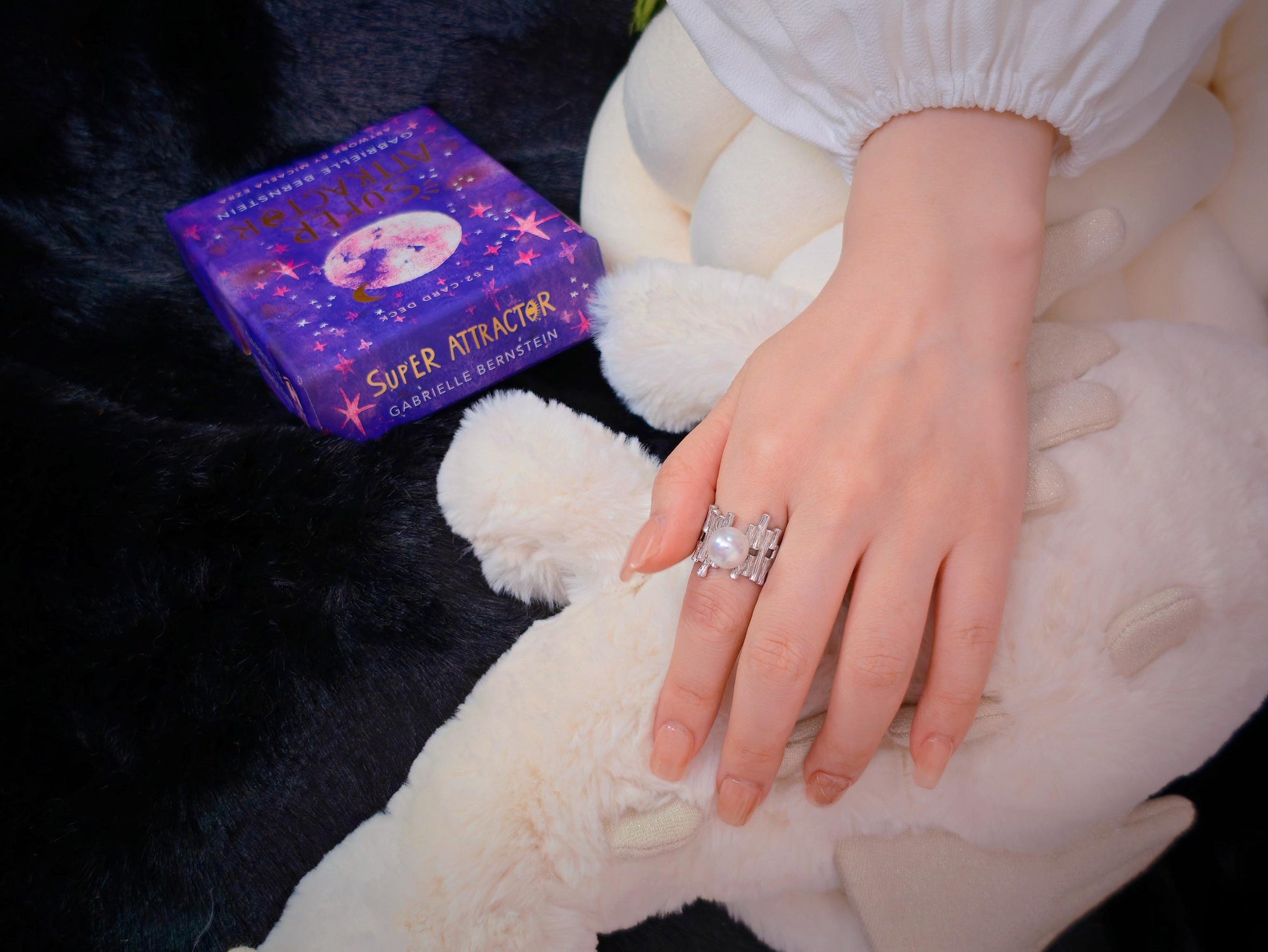 Cyrene by Elsie Palisade Pearl Ring worn on hand, styled alongside an oracle card deck on a plush background