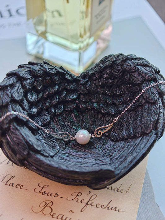 Cyrene Pinion Pearl Bracelet on dark wing base with perfume background, sterling silver and freshwater pearl bracelet