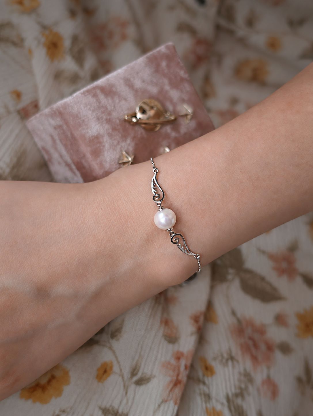 Pinion Pearl Silver Wing Bracelet worn on wrist, showing its freshwater pearl and delicate sterling silver wing details