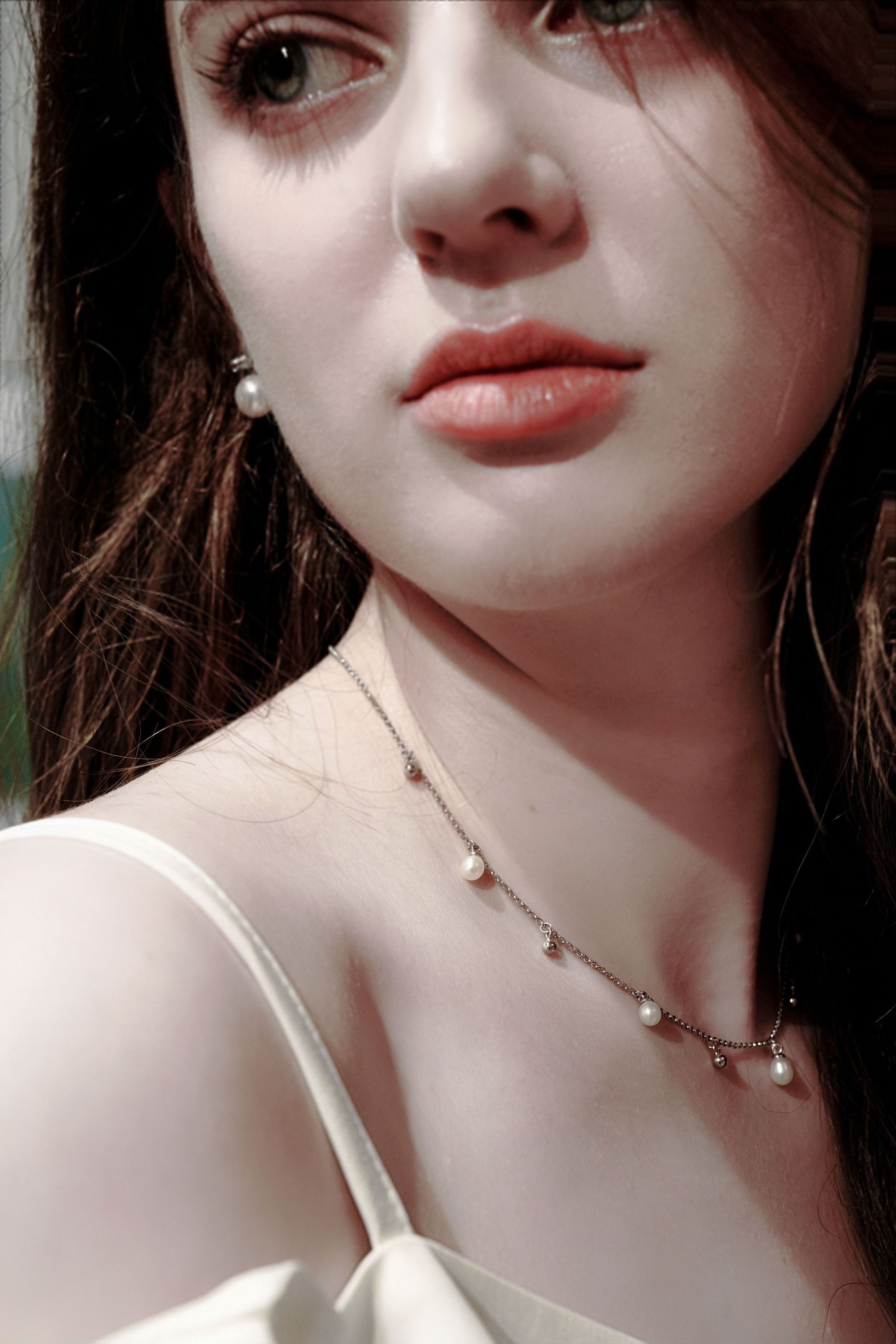 Model wearing Cyrene's romantic teardrop pearl and silver bead necklace, adding a touch of intellectual chic to a delicate white top