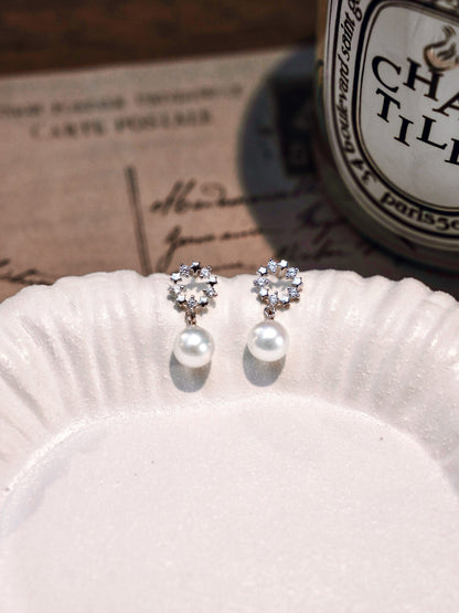 Romantic vintage aesthetic showcasing Cyrene's delicate crown pearl studs with a radiant freshwater pearl drop