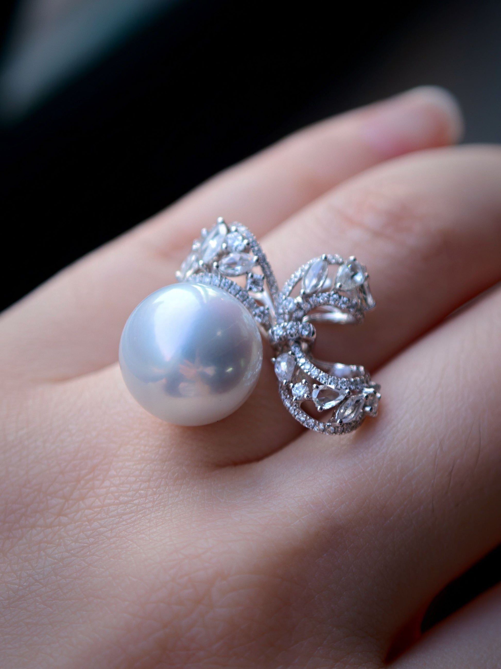 Cyrene Solitaire Bow Pearl Ring close-up on finger — flawless round South Sea pearl with diamond bow detail