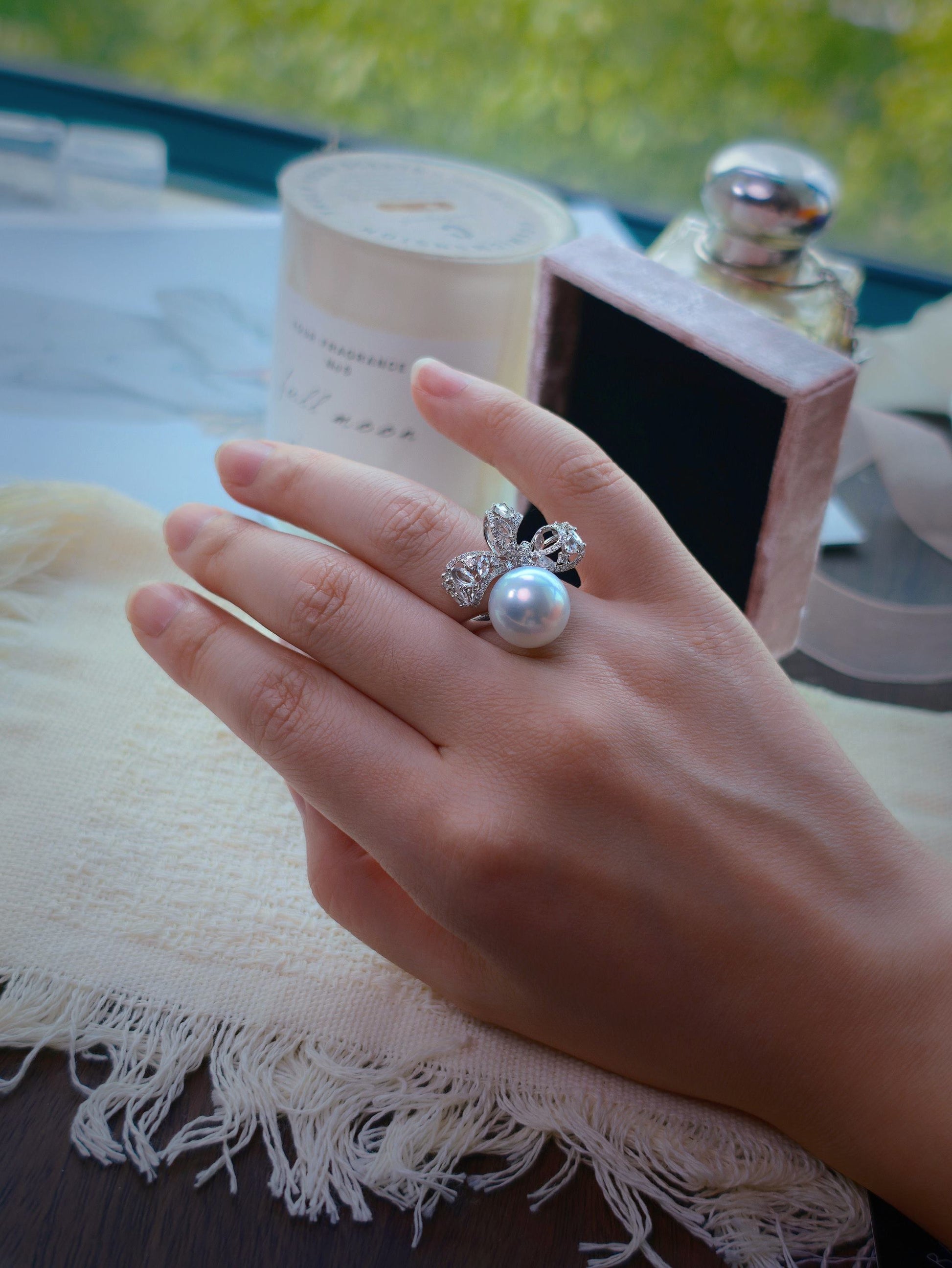 Cyrene Solitaire Bow Pearl Ring worn on hand — 18K white gold diamond bow with rare silver-blue South Sea pearl