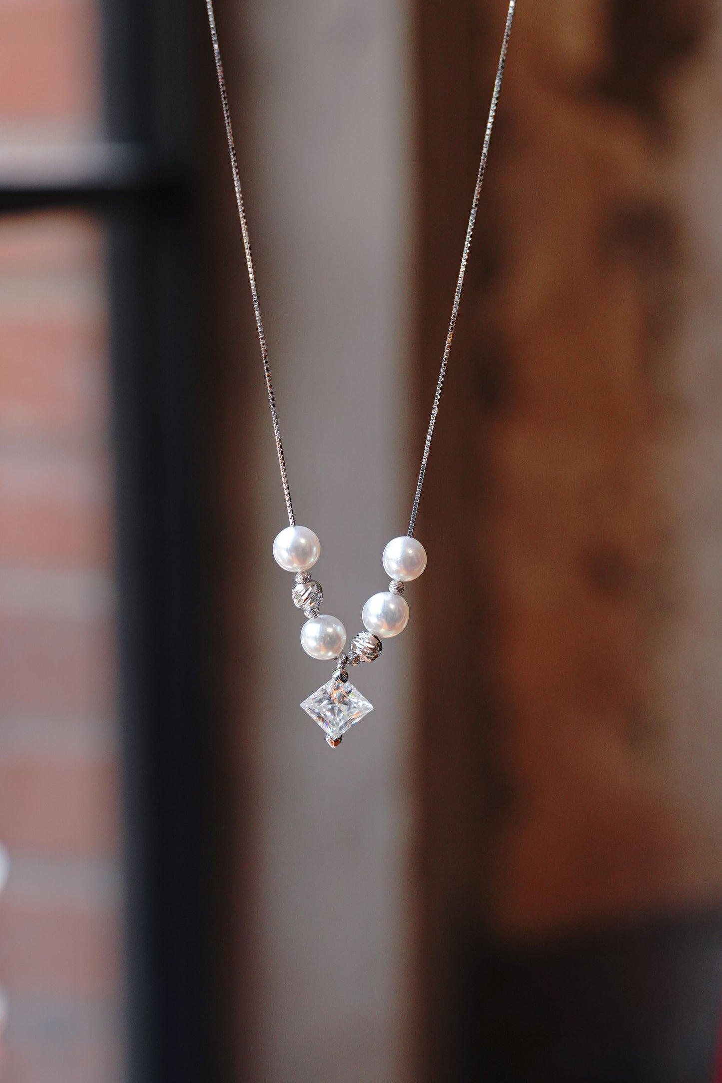 A minimalist 925 sterling silver necklace featuring a sparkling square moissanite and a round pearl.