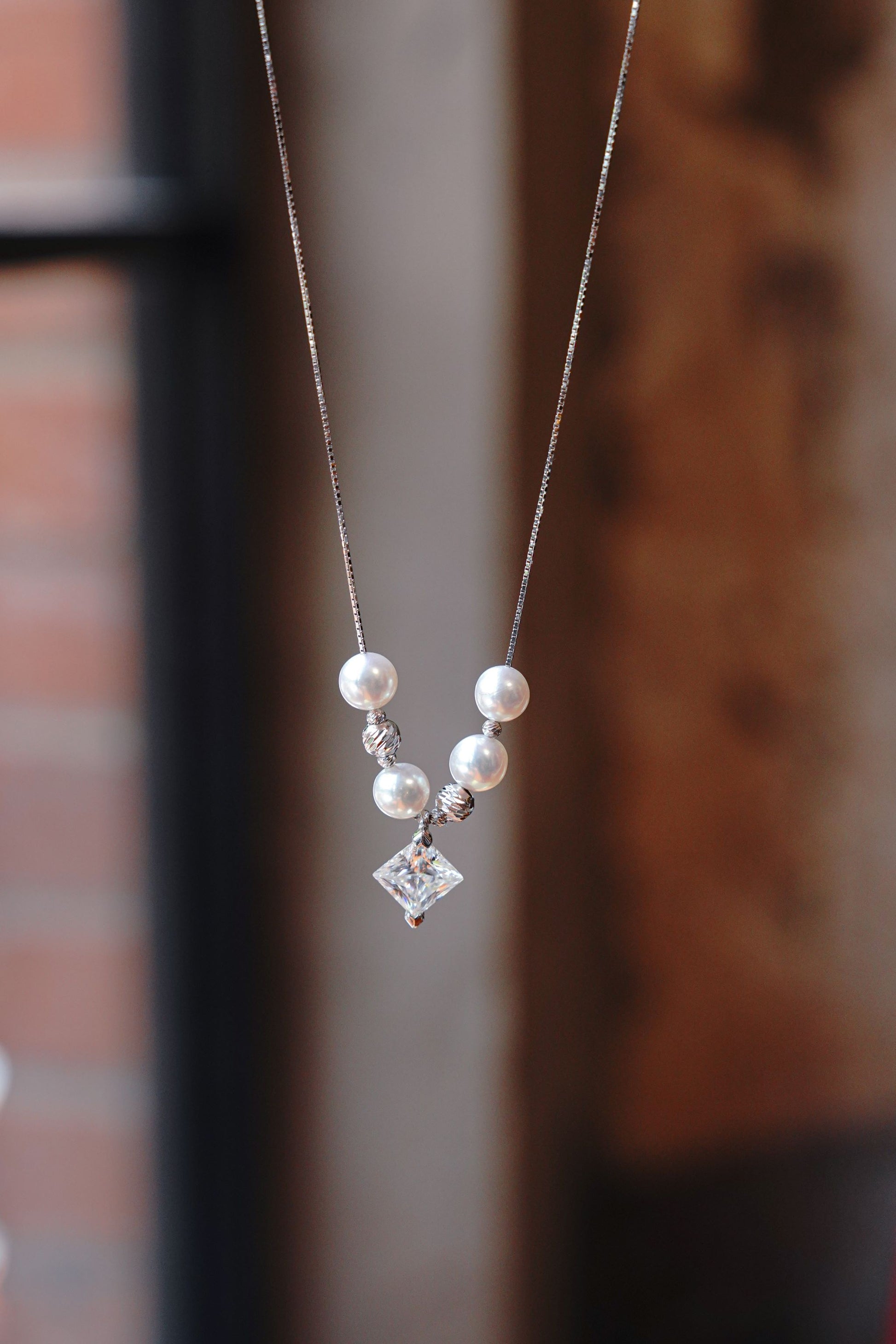 A minimalist 925 sterling silver necklace featuring a sparkling square moissanite and a round pearl.