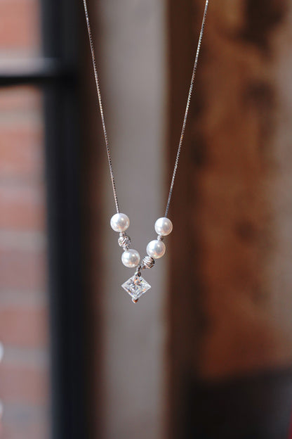 A minimalist 925 sterling silver necklace featuring a sparkling square moissanite and a round pearl.