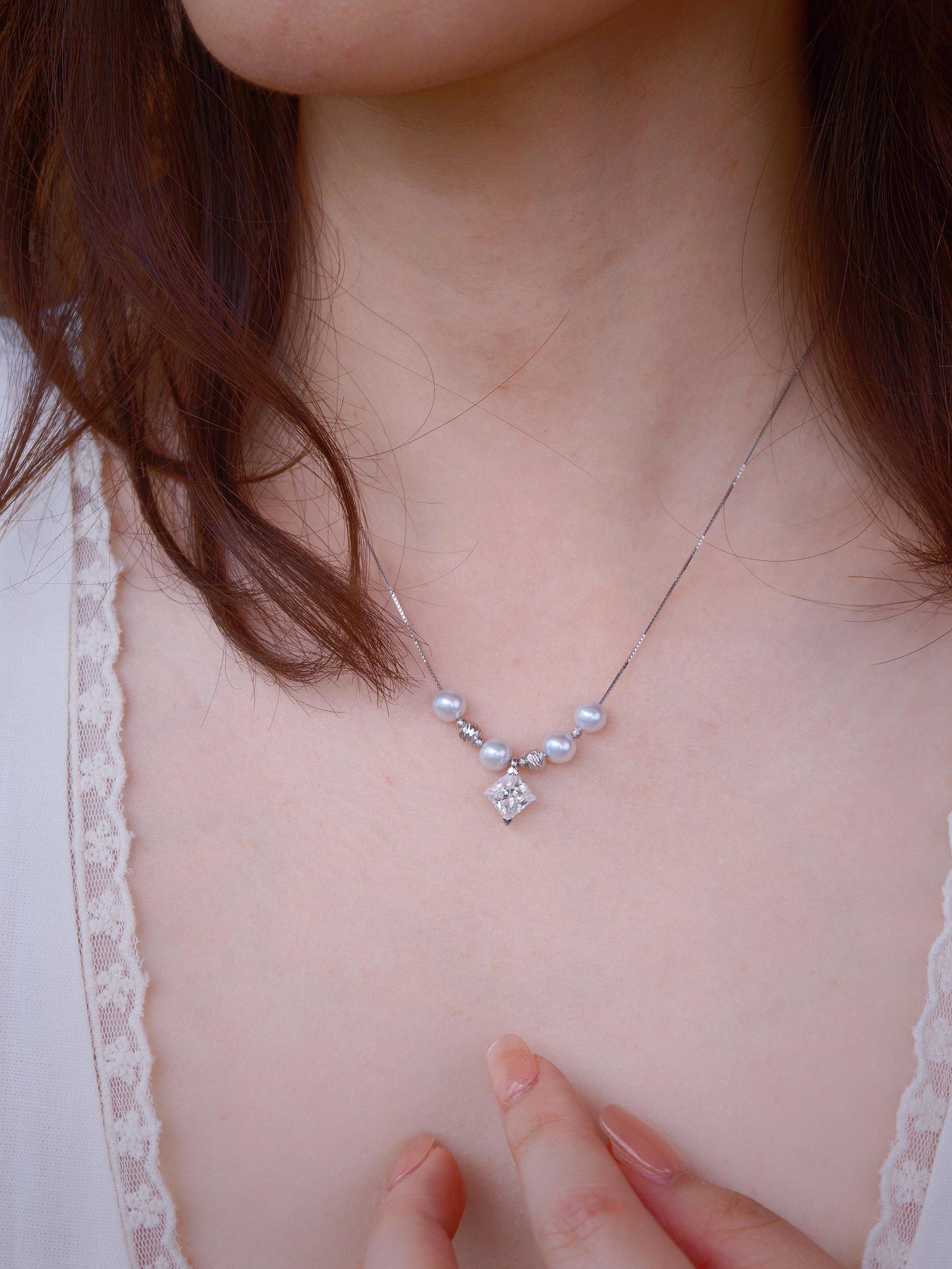 Close-up of Cyrene Tension Pearl Necklace pendant on model neck, aurora pearls and moissanite geometric stone