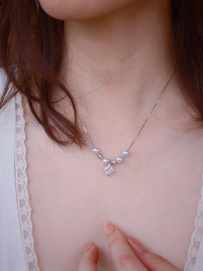 Close-up of Cyrene Tension Pearl Necklace pendant on model neck, aurora pearls and moissanite geometric stone