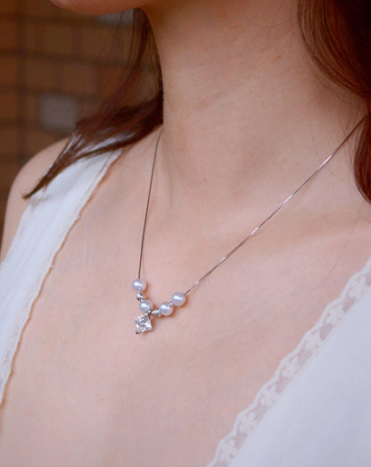 Model wearing Cyrene Tension Pearl Necklace, aurora freshwater pearls with princess-cut moissanite pendant