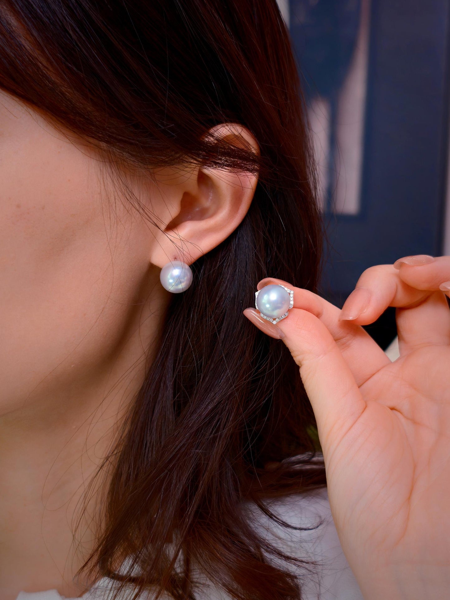Cyrene Trio Bloom Pearl Earrings worn on ear with matching pearl held alongside — rare silver-blue South Sea pearl pair
