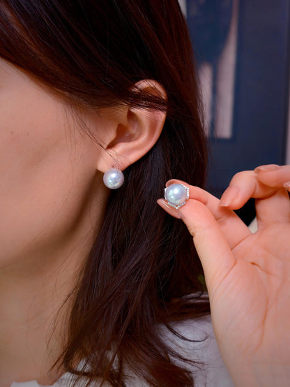 Cyrene Trio Bloom Pearl Earrings worn on ear with matching pearl held alongside — rare silver-blue South Sea pearl pair