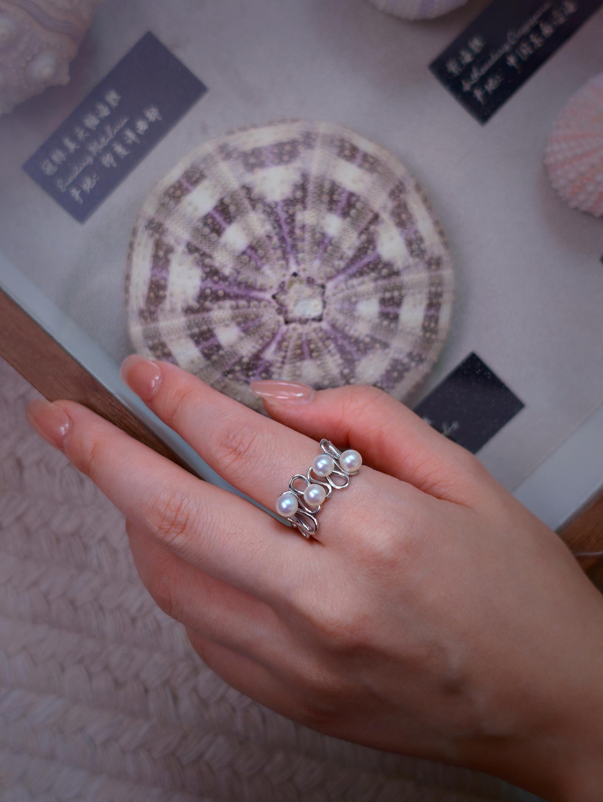 Cyrene Waveset Pearl Ring overhead view on hand — four-pearl wave band in 925 silver, open adjustable fit