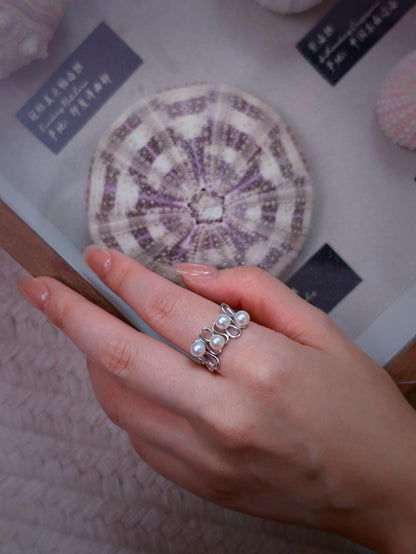 Cyrene Waveset Pearl Ring overhead view on hand — four-pearl wave band in 925 silver, open adjustable fit