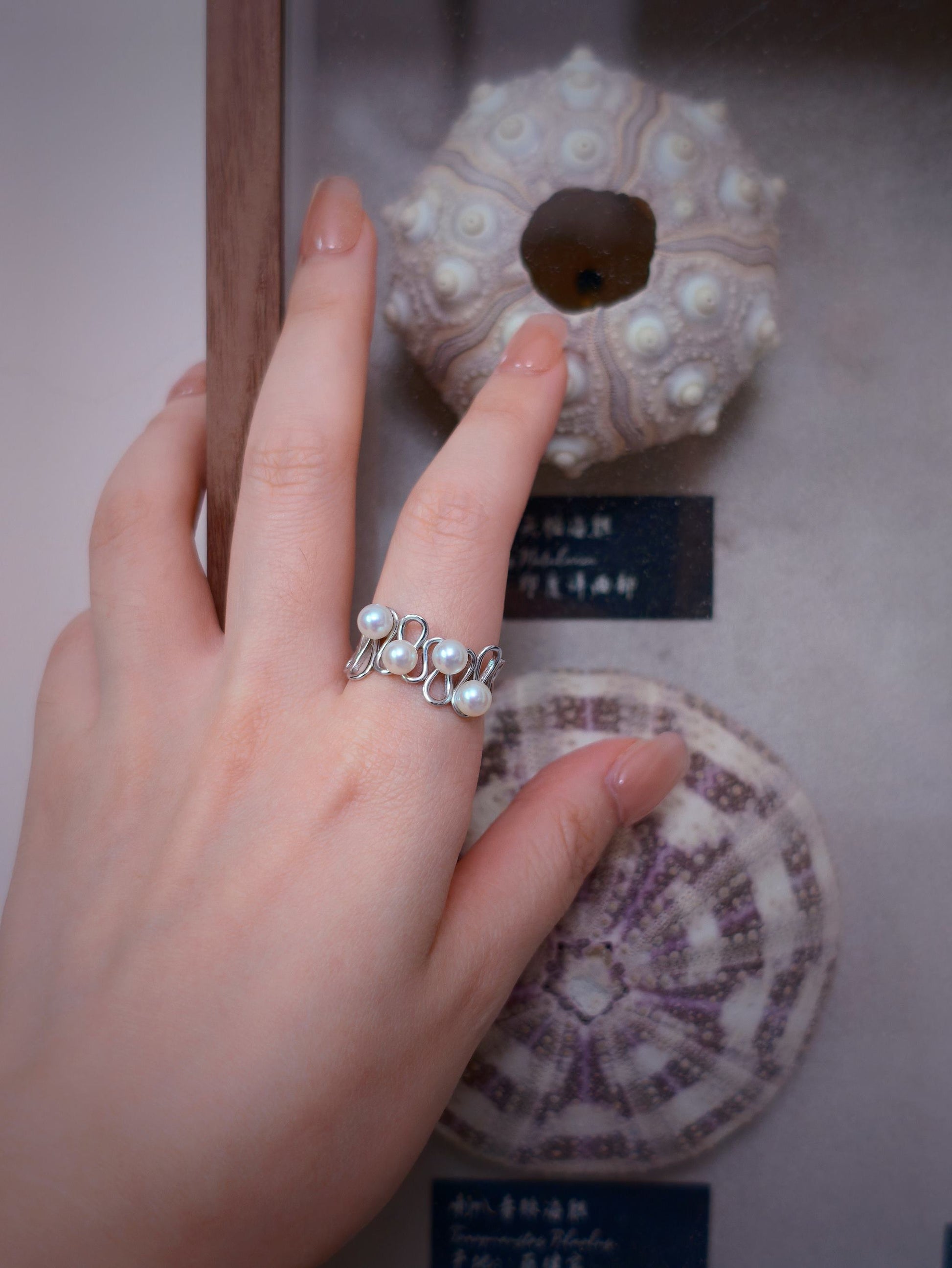 Cyrene Waveset Pearl Ring on hand against natural specimen display — sterling silver and freshwater pearl open ring